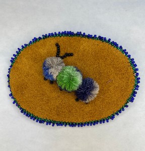 Caribou tufted pendant with beaded edge.