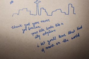 Andrea Gibson poem copied on paper alongside Toronto skyline. Reads "Thank god you never got braces. Your bite looks like a city skyline. I bet you'll leave that kind of mark on the world."