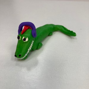 A clay crocodile with red hair and purple headphones.
