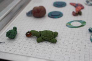 Tray of metal clay pieces with small clay turtle in foreground.